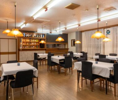 Interior dining area with white-tablecloth tables, pendant lamps and wooden floor at Elan Hotel Lake Nojiri Nagano