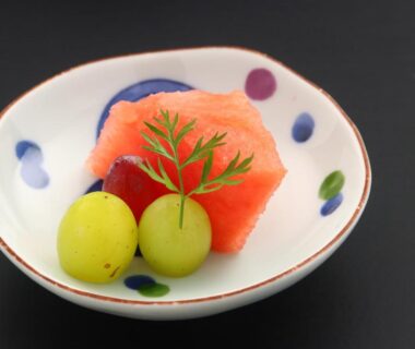 Small ceramic bowl with watermelon and two green grapes, garnished with herb sprig at Ena Totaro, Gifu