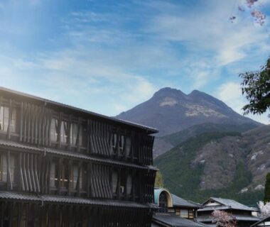 Wooden ryokan exterior with mountain backdrop at Enokiya Ryokan, Ōita, Kyūshū, Japan