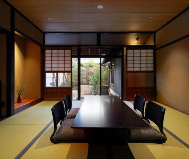Traditional tatami room with low table, floor chairs and shoji screens opening to a small courtyard garden at Enso Machiya