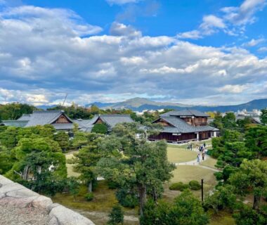 Manicured garden and wooden ryokan buildings at Enso Machiya, Kyoto with pine trees and distant hills
