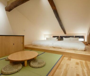 Tatami seating area with low round table and raised bed platform at Enso Machiya in Kyoto