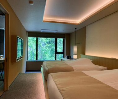 Twin beds and seating by window at Exclamation Hotel in Hokkaidō, Japan