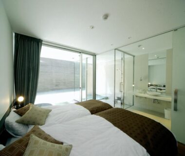 Twin beds with glass-partition bathroom and sliding door to outdoor terrace at Four Seasons Yuzawa, Niigata
