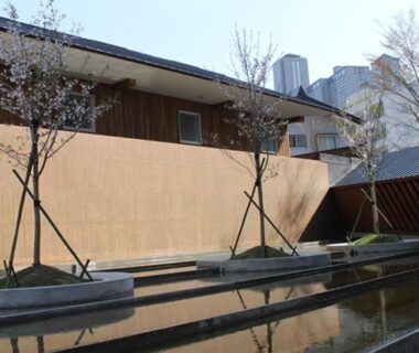 Reflecting pool courtyard at Four Seasons Yuzawa Quattro with wooden facade, trees and city skyline in Niigata