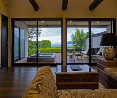 Sofa seating and low table facing glass doors to terrace, garden and distant hills at Fugaku Gunjo Shizuoka