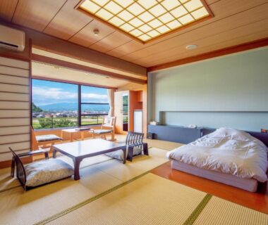 Tatami room with futon, low table and shoji screens, window overlooking mountain landscape at Fugaku Hanabusa, Shizuoka