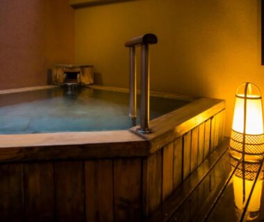 Traditional indoor wooden bath lit by a floor lantern in a ryokan room at Fugaku Hanabusa, Shizuoka.