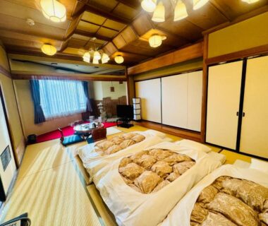 Tatami room with futon bedding, low table and sliding doors at Fuji Green Hotel in Shizuoka, Chūbu