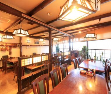 Warm wooden dining area with tables, shoji screens and ceiling beams in a ryokan in Shizuoka, Chūbu