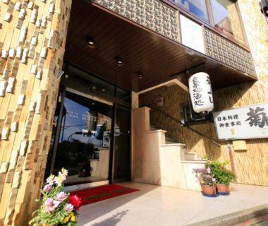 Tiled facade and glass entrance with lantern, red mat and potted plants at Fuji Green Hotel Shizuoka
