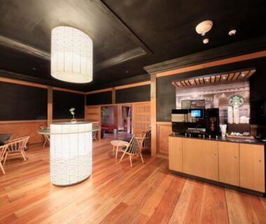 Lobby and lounge with wooden floors, central illuminated column, seating and beverage station at Fuji Onsenji Yumedono, Yamanashi