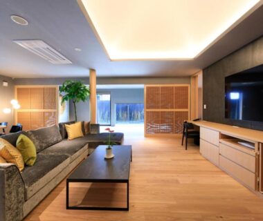 Spacious living room at Fuji Onsenji Yumedono with sofa, low table, TV and sliding wooden screens in Yamanashi