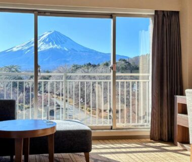 Room interior with seating area and balcony framing Mount Fuji over Yamanashi landscape