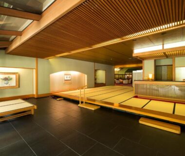Spacious tatami seating area with raised platforms, low wooden benches and traditional wall art at Fujiiso, Nagano