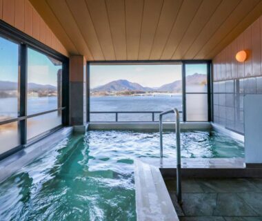 Indoor onsen bath with large windows overlooking lake and mountains at Fujikawaguchiko Onsen Hotel Asafuji Yamanashi