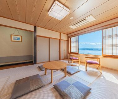 Sunlit tatami room with low table, zabuton cushions and shoji screens at Fujikawaguchiko Onsen Hotel Asafuji, Yamanashi