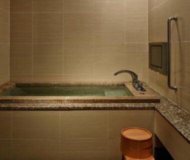 Stone-lined indoor bath with wooden stool at Fujikawaguchiko Onsen Konanso, Yamanashi