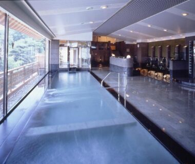 Long indoor onsen bath with windows and washing stations at Fujikawaguchiko Onsen Konanso, Yamanashi