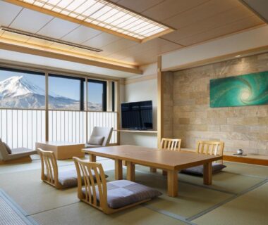 Spacious tatami room with low table, floor chairs and balcony framing Mount Fuji in Yamanashi