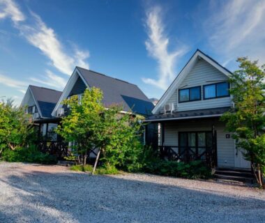 Row of pitched-roof cottages at Fujimien with gravel forecourt and landscaped trees under blue sky