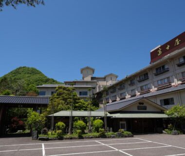 Multi-story ryokan building Fujiya with entrance canopy, parking and mountain backdrop in Niigata Chūbu