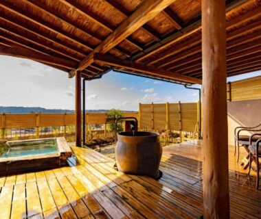 Covered wooden terrace with soaking tub, chairs and distant mountain view at Fujiya, Ishikawa, Chūbu