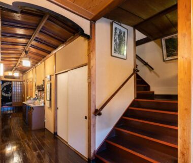 Interior corridor with polished wooden floors, staircase, sliding doors and warm lighting at Fujiya Ryokan Kyoto