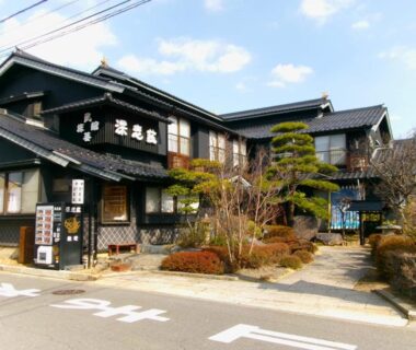 Wooden ryokan exterior with entrance, shrubs, and signage at Fukashiso in Nagano, Chūbu, Japan