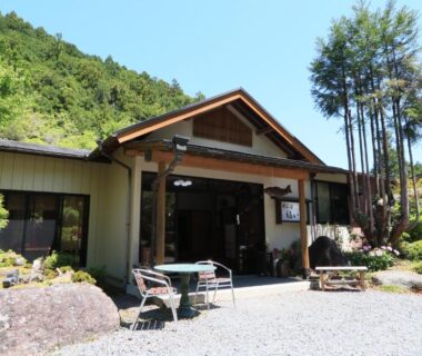 Gravel courtyard and outdoor seating at Fukuichi ryokan with surrounding forested hills in Yamanashi