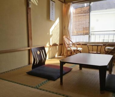 Tatami room with low table, floor cushions and rattan chairs by window at Fukushimakan, Kanagawa, Kantō, Japan