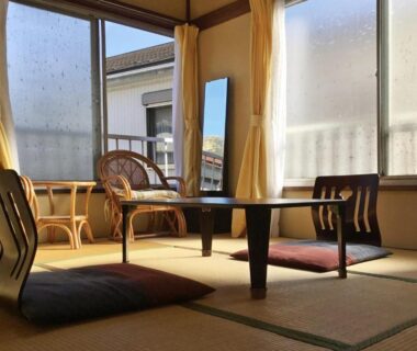 Traditional tatami room with low table, floor cushions and wicker chairs by windows at Fukushimakan, Kanagawa