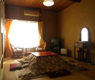 Traditional tatami room with kotatsu table, low chairs by bright window and wooden vanity at Fukushimakan, Kanagawa