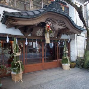 Carved wooden gable entrance with kadomatsu decorations and sliding doors at Fukuzumiro ryokan in Kanagawa Japan