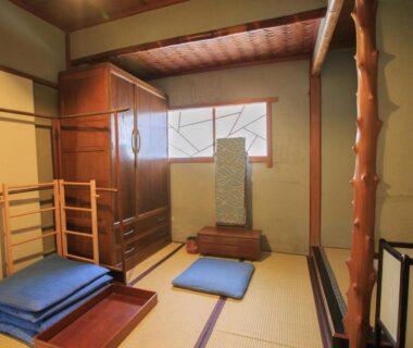 Traditional tatami room with floor cushions, wooden beams, shoji window and low chest at Fukuzumiro in Kanagawa