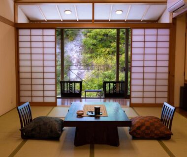 Tatami room with low table, zabuton cushions and shoji doors opening to green garden at Fulsato, Iwate