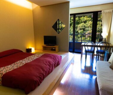 Low platform bed, seating area and balcony overlooking greenery at Fulsato in Iwate, Tōhoku