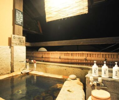 Stone onsen bath with wooden fence and soap bottles at Fumoto Ryokan, Kumamoto, Kyushu
