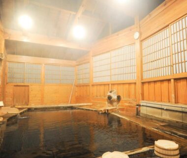 Indoor wooden onsen bath with shoji screens, stools, and warm lighting at Fumoto Ryokan in Kumamoto, Kyūshū