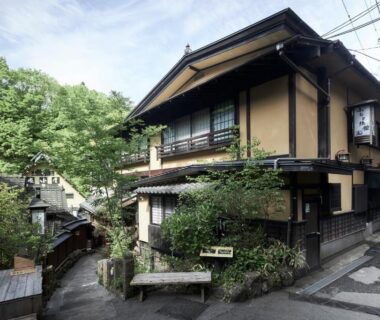 Wooden two-story ryokan exterior with stone steps and greenery at Fumoto Ryokan in Kumamoto, Kyushu
