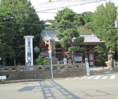 Stone and wooden temple gate with tiled roof and greenery by a roadside near Funayado Akitaya Kanagawa