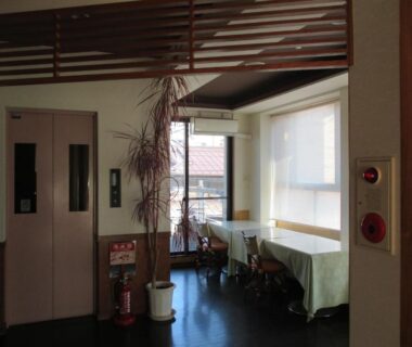 Small ryokan lobby with elevator, potted plant and window seating at Funayado Akitaya, Kanagawa