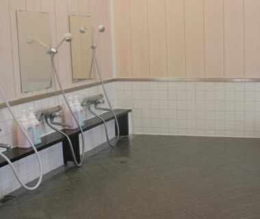 Indoor communal wash stations with handheld showers and stools at Fureaihouse Shiodu no Sato, Niigata