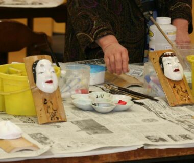 Two traditional masks on stands with artisan hands at Fureaihouse Shiodu no Sato Niigata