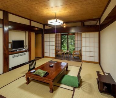 Traditional tatami room with low wooden table, zabuton cushions, shoji screens and garden view at Furusato in Gifu