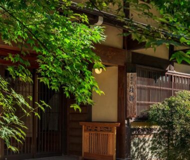 Wooden lattice entrance with lush foliage at Furusato ryokan in Gifu, Chūbu
