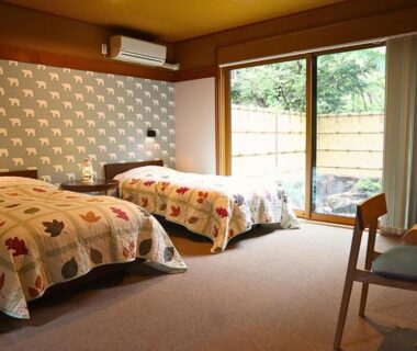 Two-bed room with sliding glass door to small fenced garden, desk and decorative wallpaper