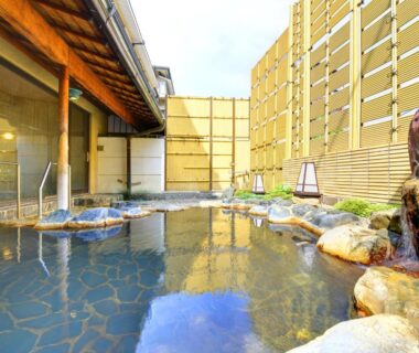 Rock-lined outdoor onsen bath with wooden fence and stone floor at Furuya Ryokan, Shizuoka, Chūbu