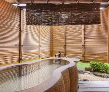 Sheltered stone bath with bamboo blinds, wooden deck and small rock garden at Furuya Ryokan, Shizuoka, Chūbu