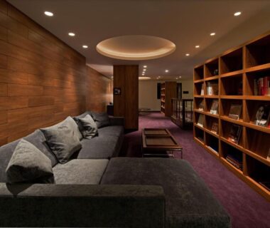 Wood-paneled lounge with sofa, low tables and bookshelf at Furuyu Onsen Oncri in Saga, Kyushu, Japan